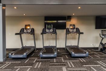 a row of treadmills in a room with a tv